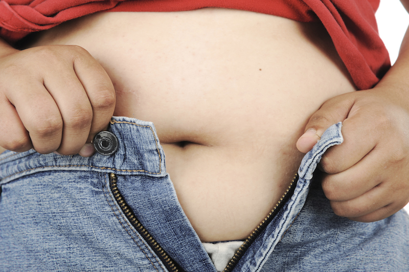 Closeup of a woman buttoning up her jeans over stomach