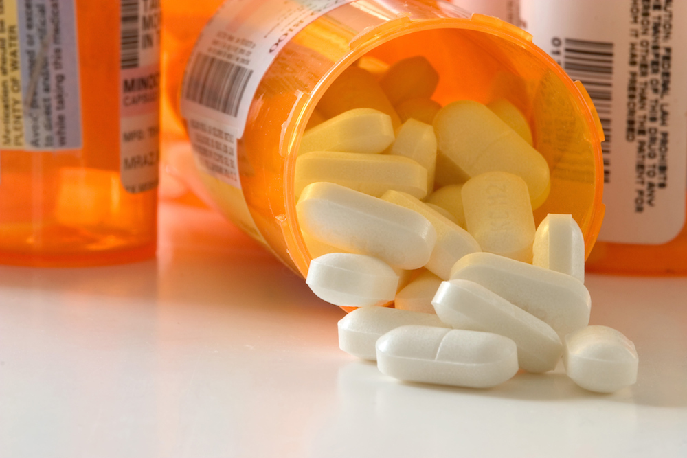 Closeup of an open prescription bottle with pills falling out